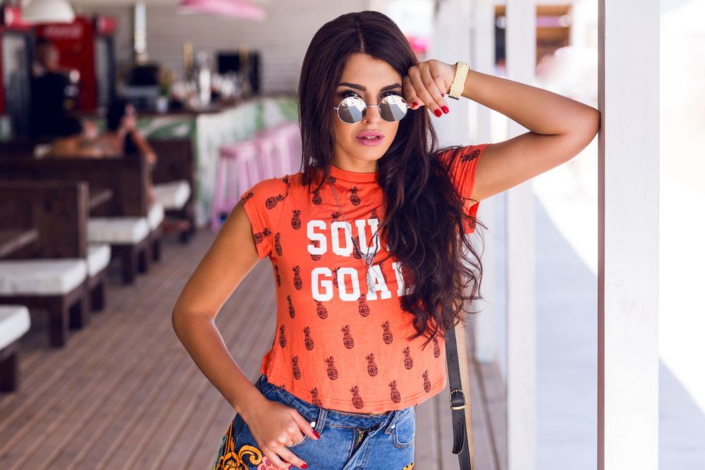 Devojka u narandžastoj majici sa printom i farmerkama u casual outfitu