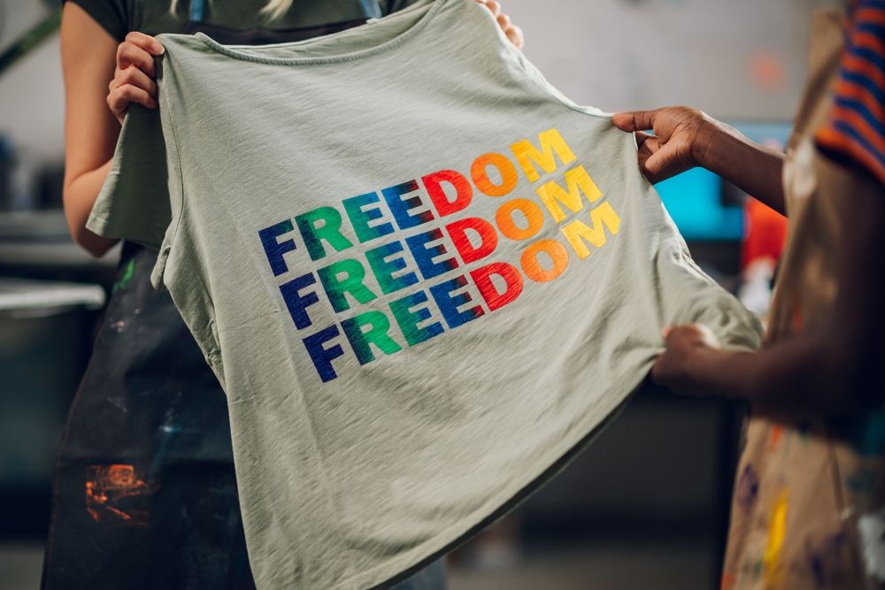 Osoba drži majicu sa velikim šarenim natpisom Freedom